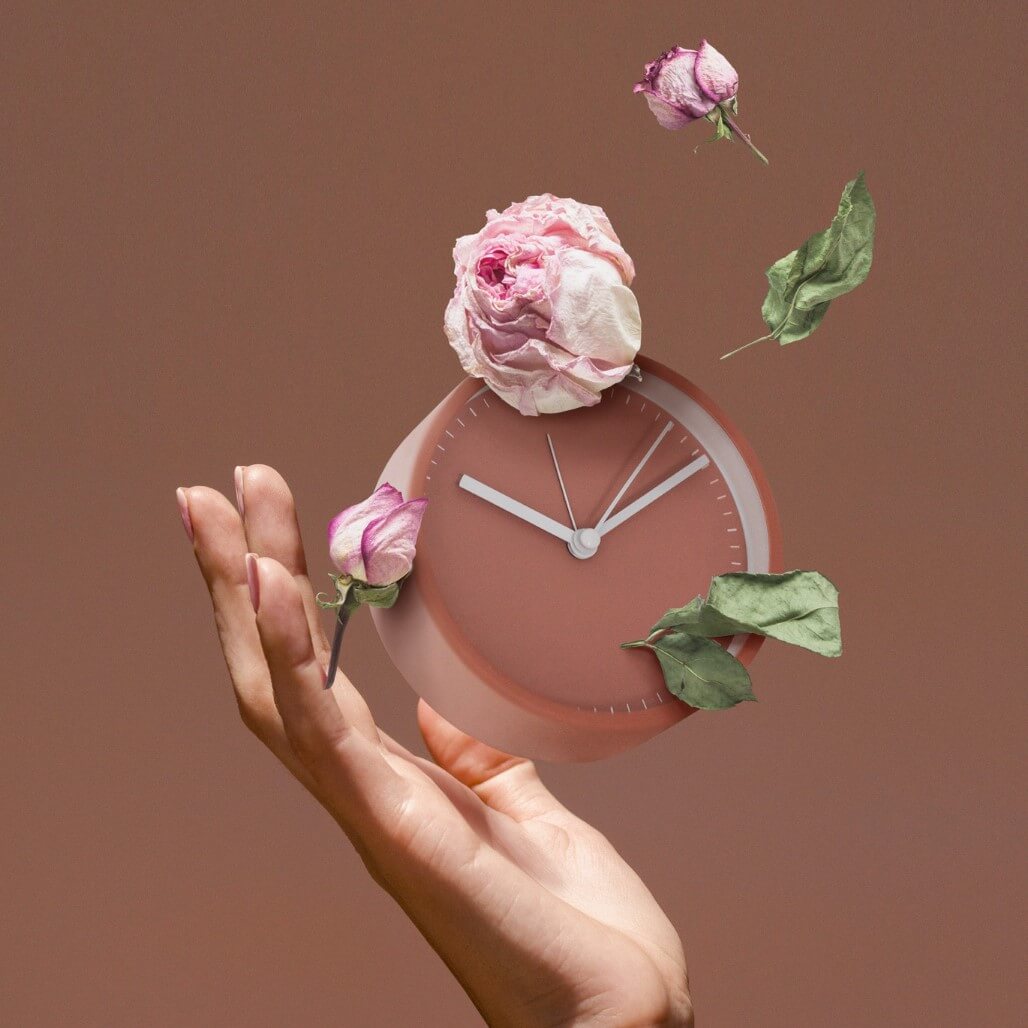 Hand houdt klok vast met bloemen als symbool voor tijd en groei