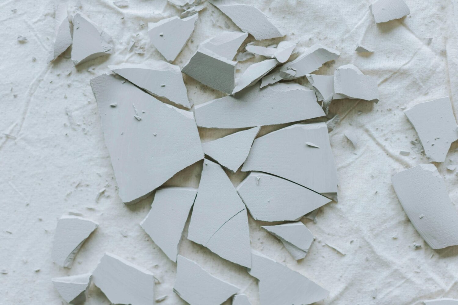 Gebroken stukken keramiek op de grond als symbool voor stress, kwetsbaarheid en mentale belasting