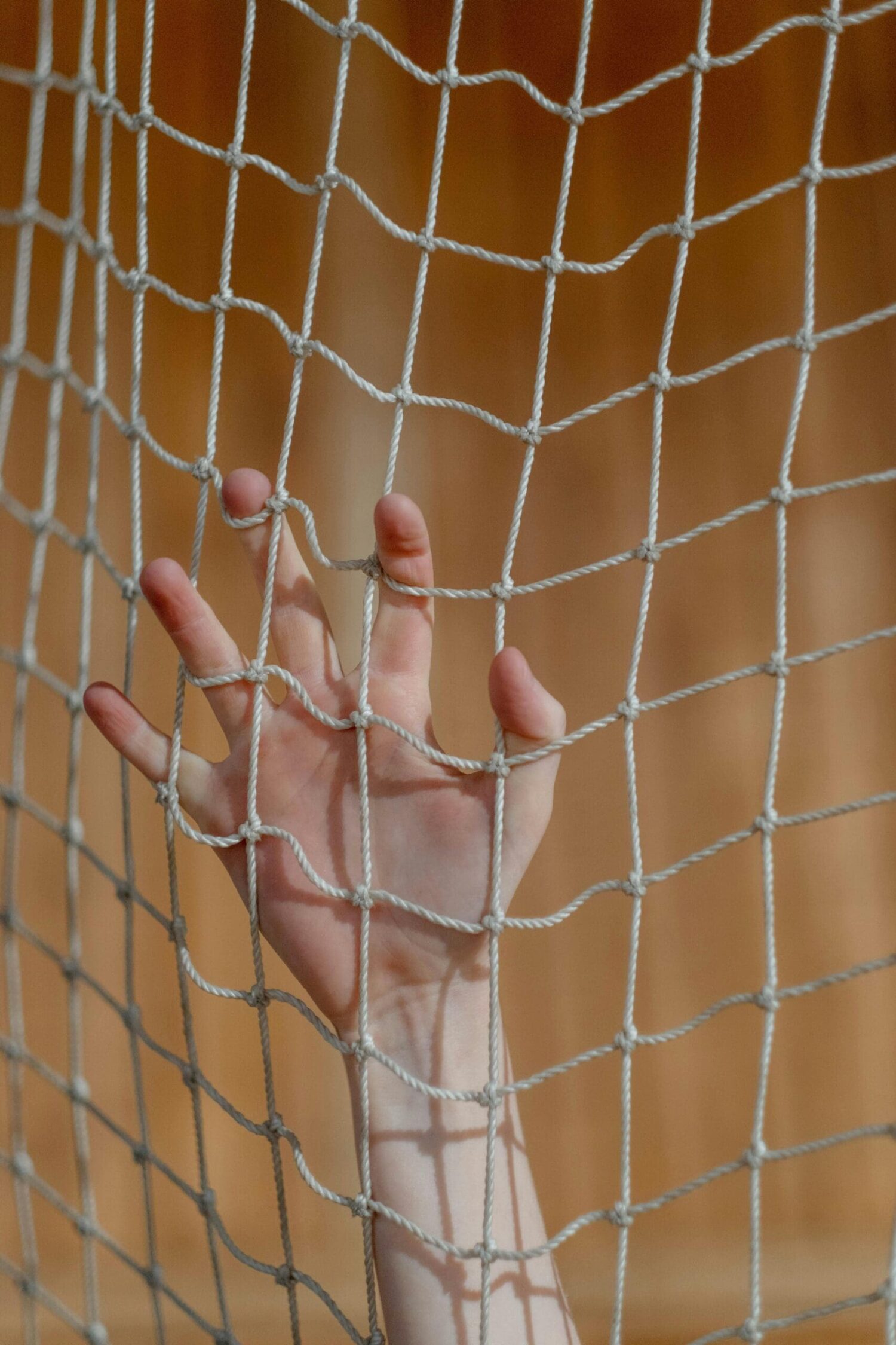 Hand achter een net als symbool voor beperking, vastzitten en mentale blokkades