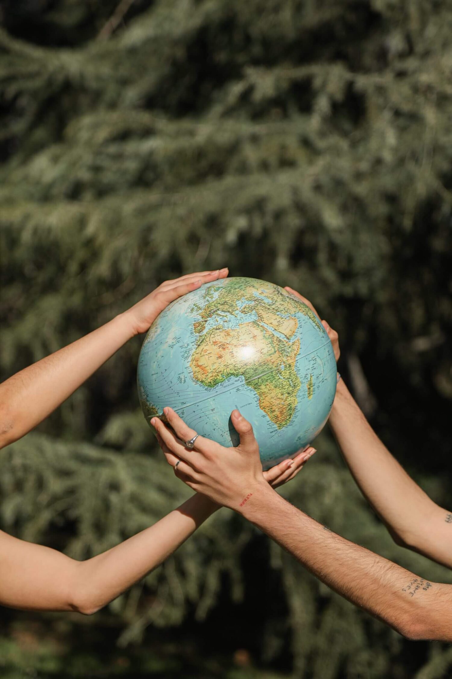 Meerdere handen die samen een wereldbol vasthouden