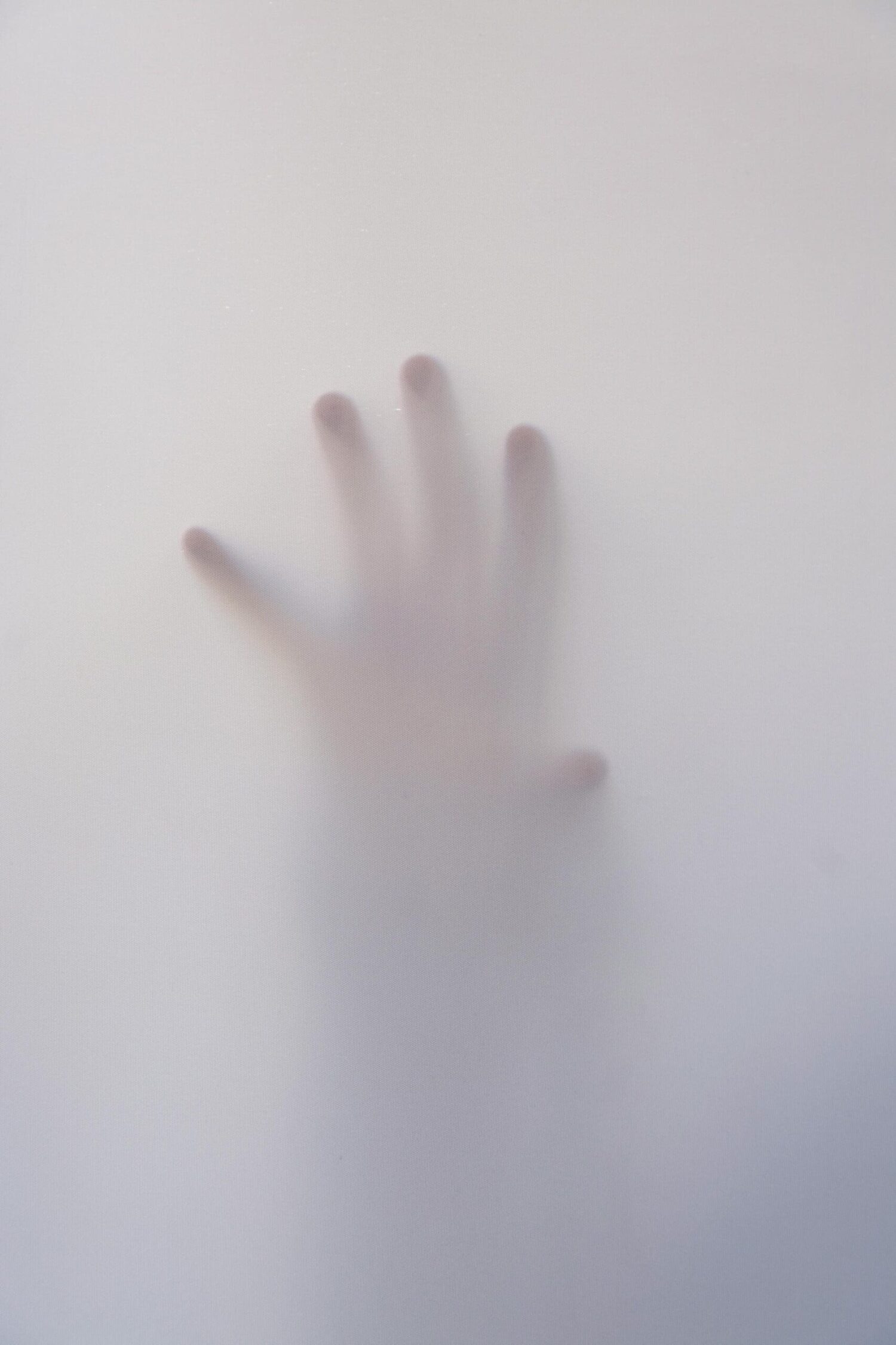 Hand zichtbaar achter een wazige, doorschijnende wand