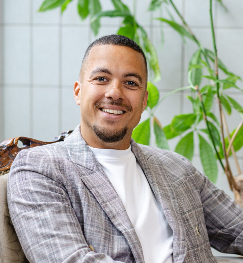 Portret van glimlachende man in geruite blazer en wit shirt in lichte werkomgeving met planten