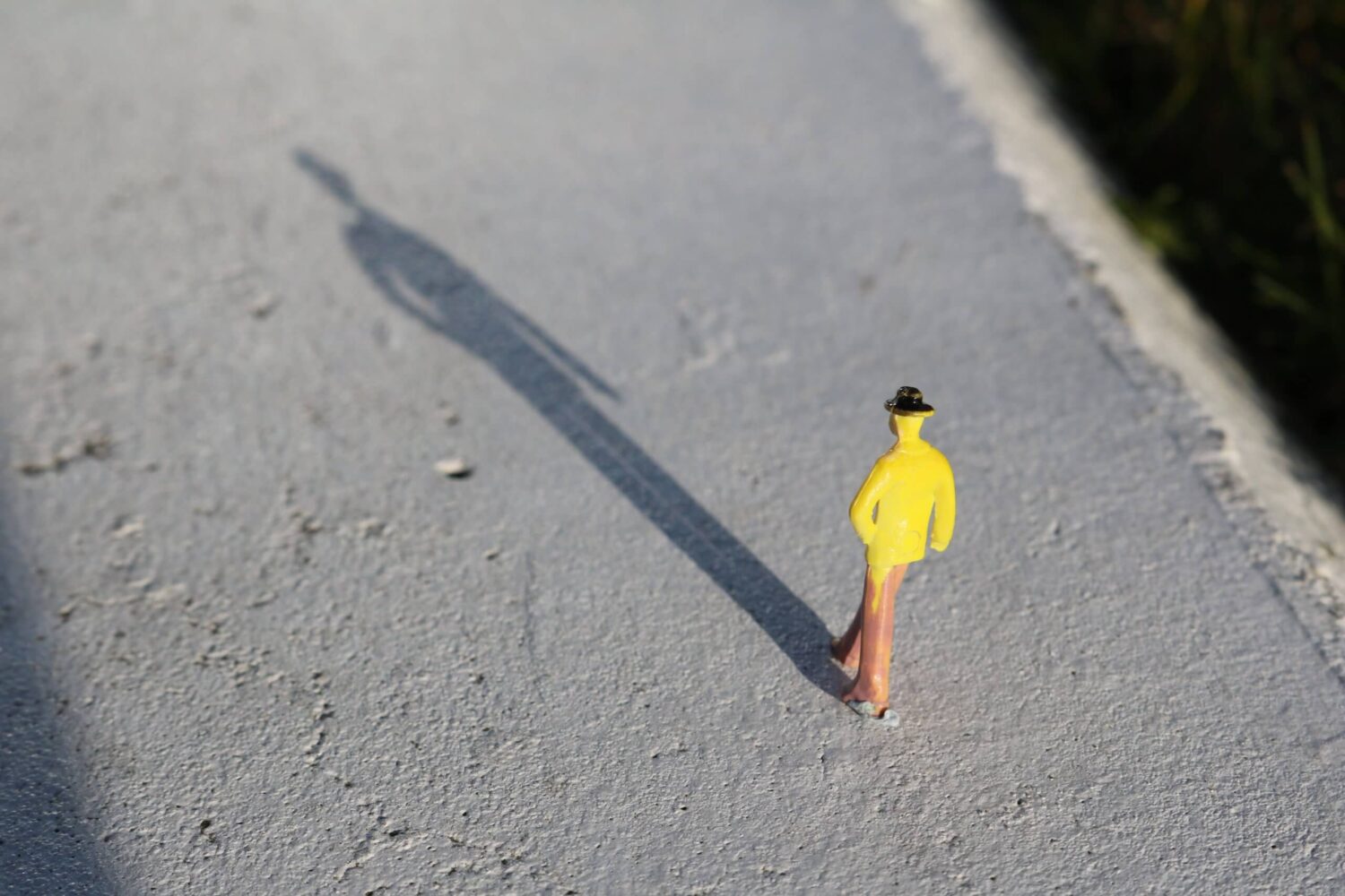 Klein figuur loopt alleen met lange schaduw, symbool voor eenzaamheid en mentale belasting