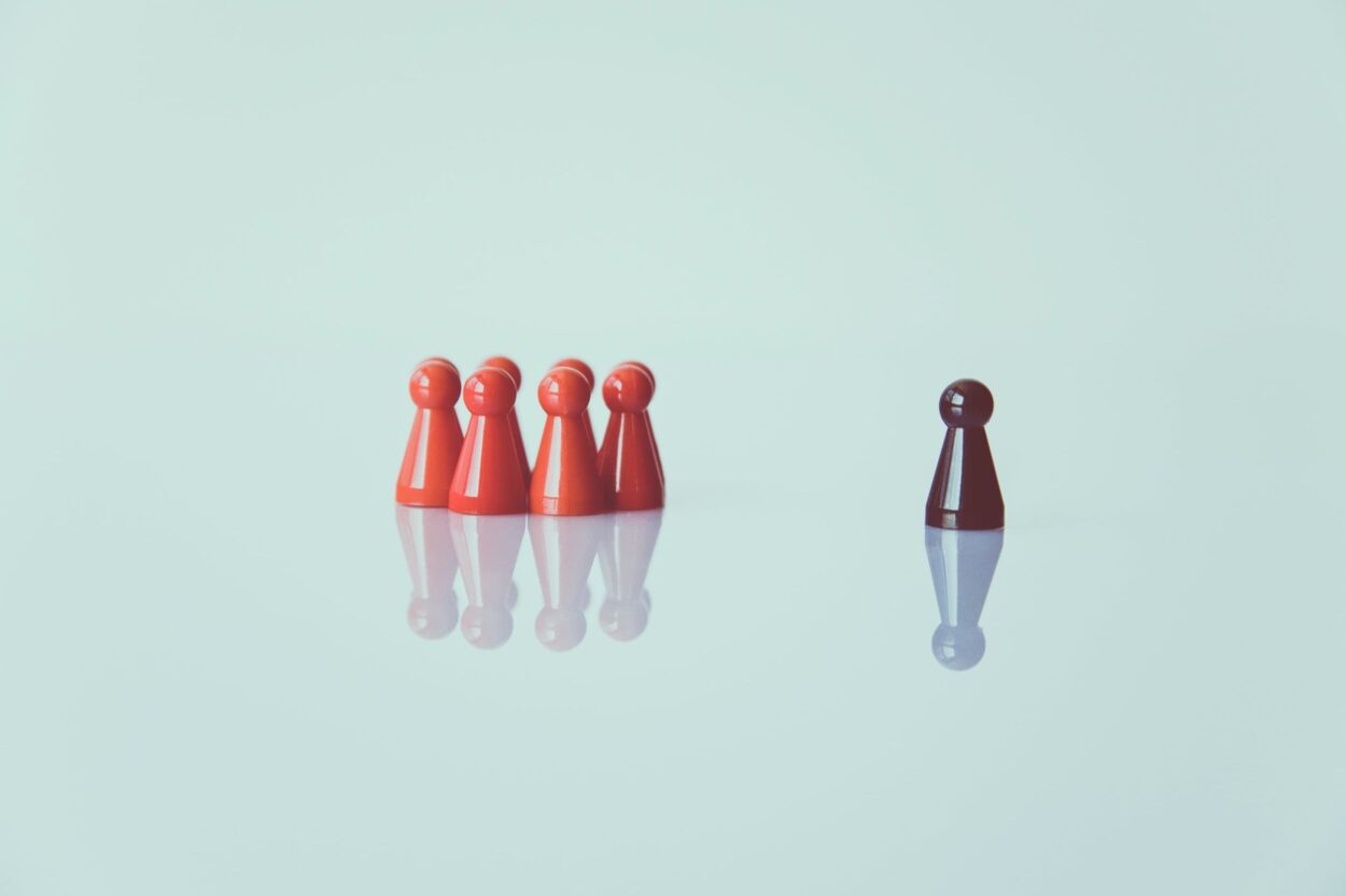 Eén persoon staat apart van een groep, symbool voor isolatie op de werkvloer