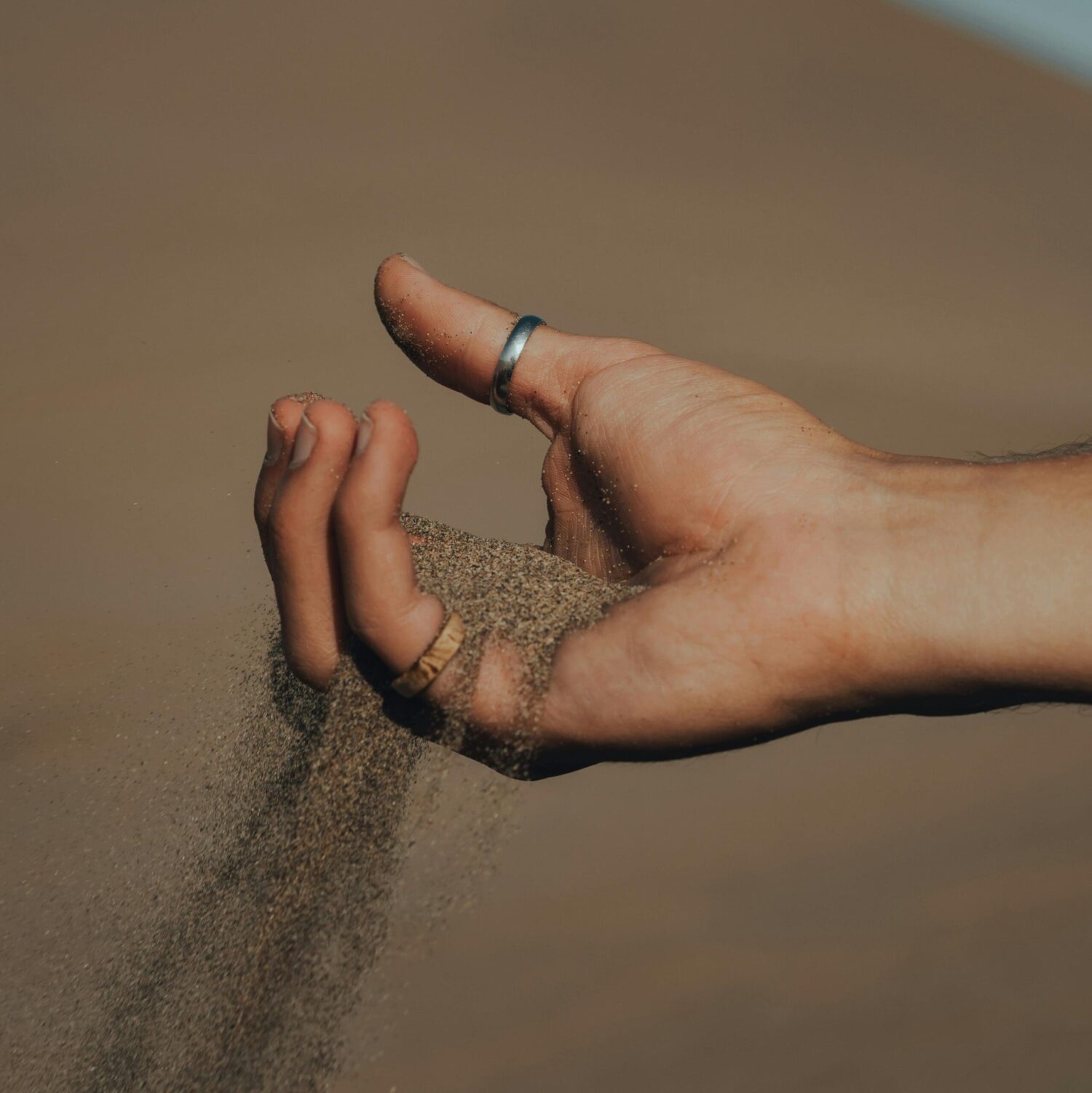 Hand waar zand langzaam door de vingers glijdt