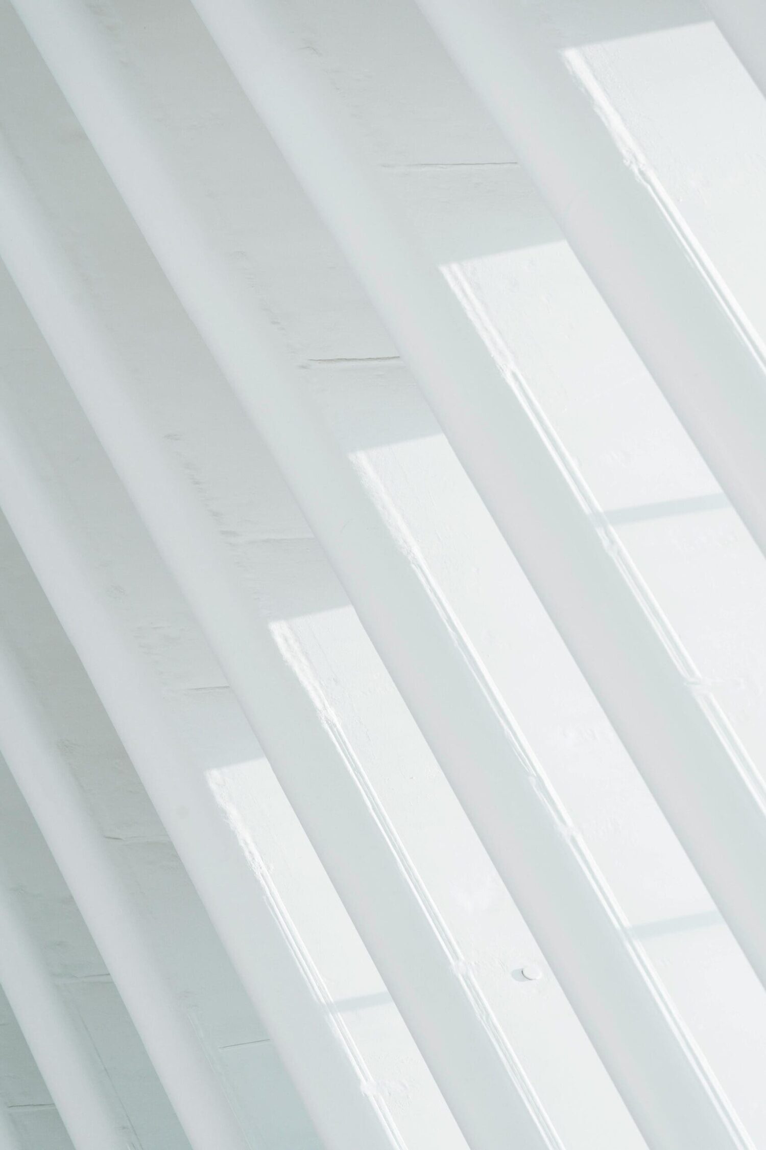 Minimalistisch interieur met lichtinval en schaduw op witte plafondbalken