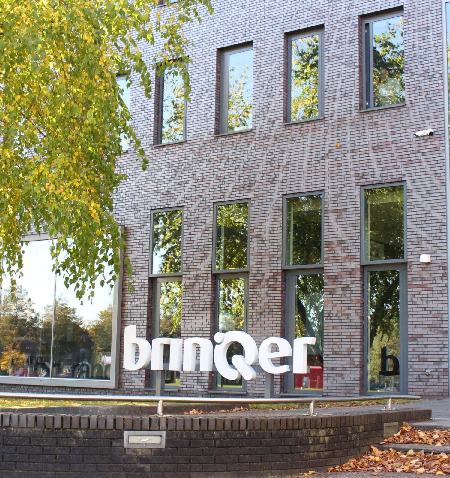 Kantoorgebouw van BrinQer met logo bij de ingang, werkomgeving gericht op welzijn en mentale gezondheid