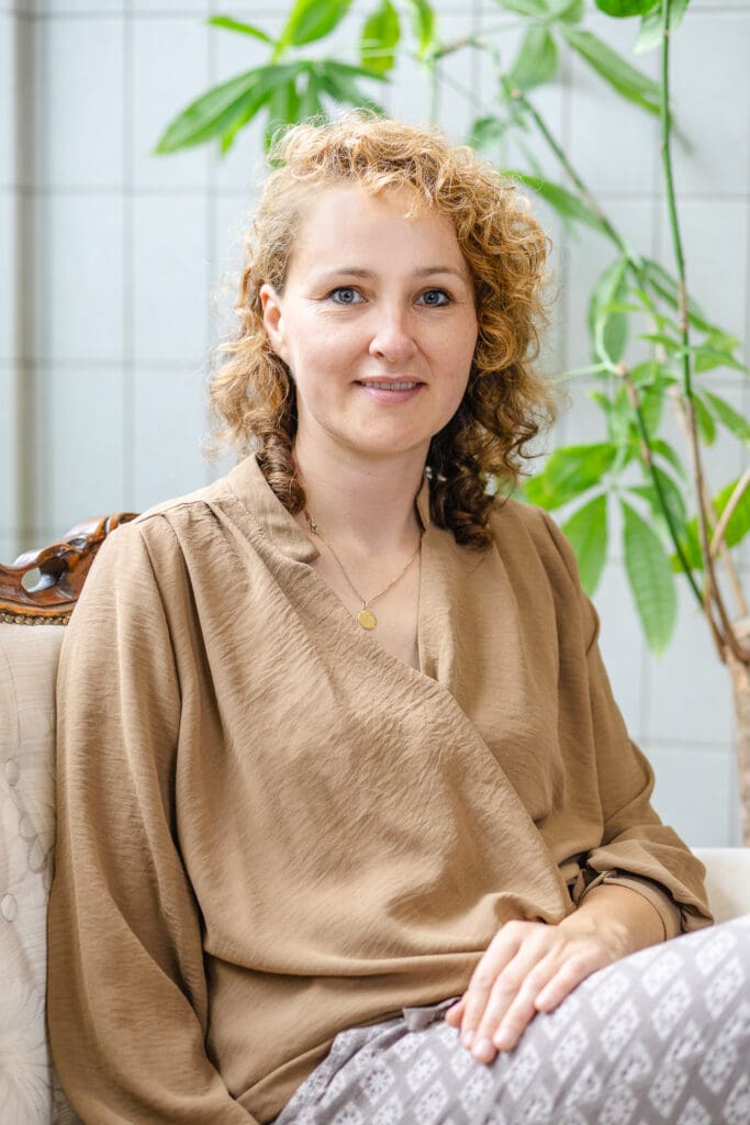 Vrouw met krullend haar en rustige uitstraling zit op stoel
