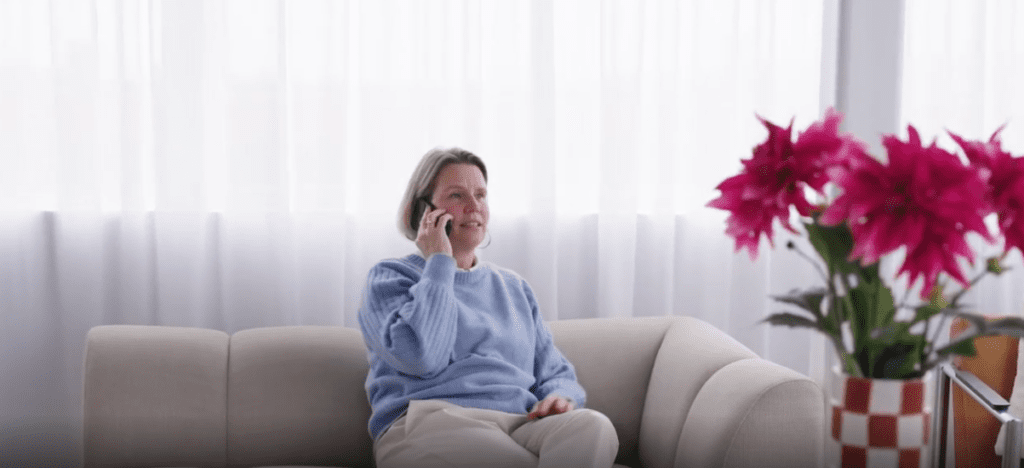 Vrouw zit op bank en voert telefoongesprek in rustige woonkamer
