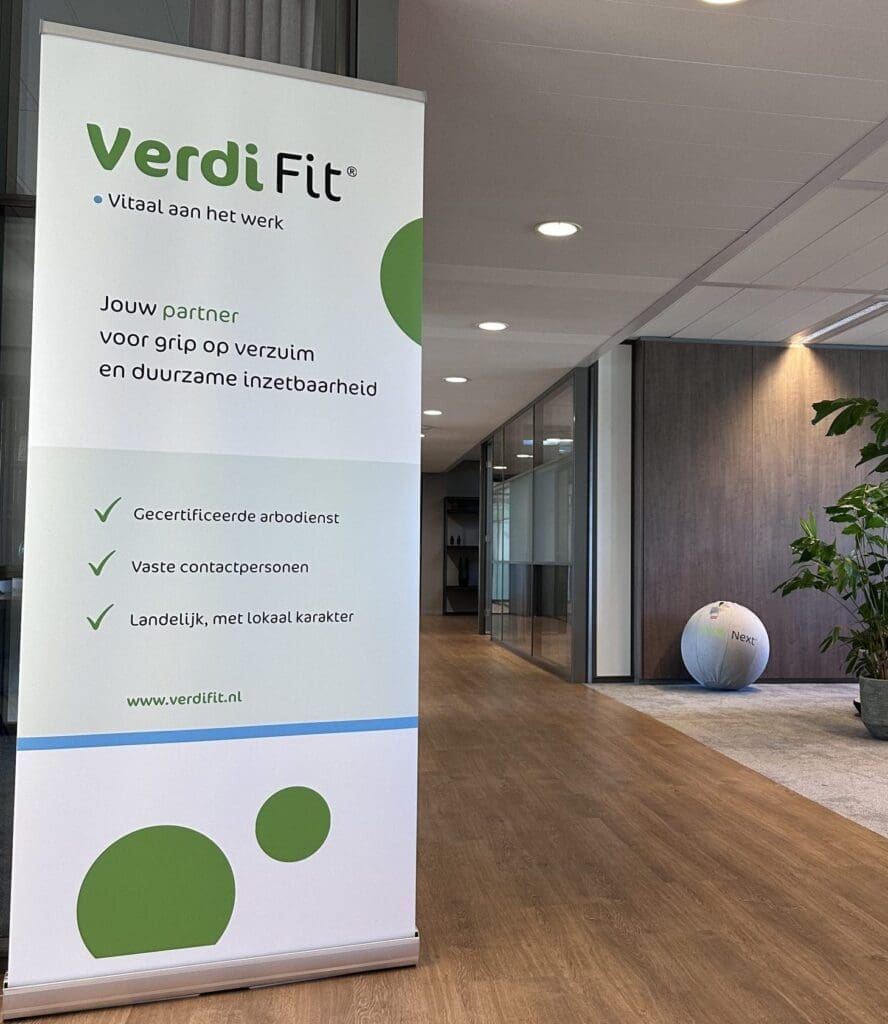Roll-upbanner van VerdiFit in een moderne kantooromgeving met de slogan 'Vitaal aan het werk'. Op de banner staat informatie over verzuimbegeleiding, duurzame inzetbaarheid en arbodienstverlening.