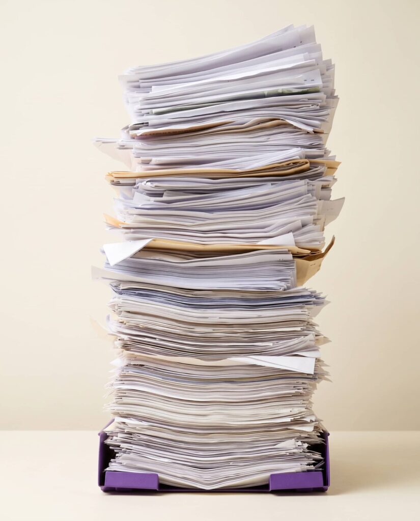 Hoge stapel documenten en dossiers in een postbak als symbool voor administratieve werkdruk