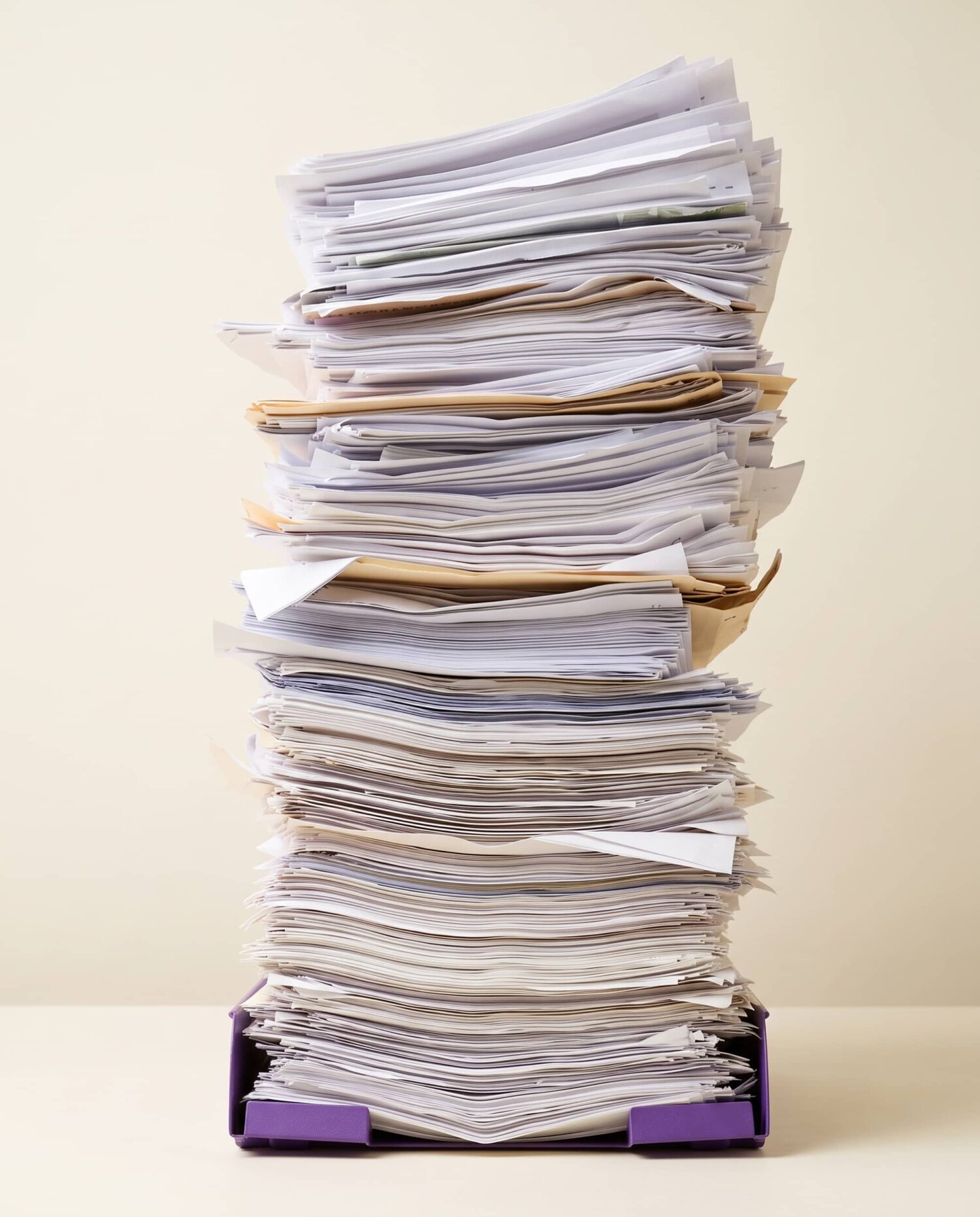 Hoge stapel documenten en dossiers in een postbak als symbool voor administratieve werkdruk